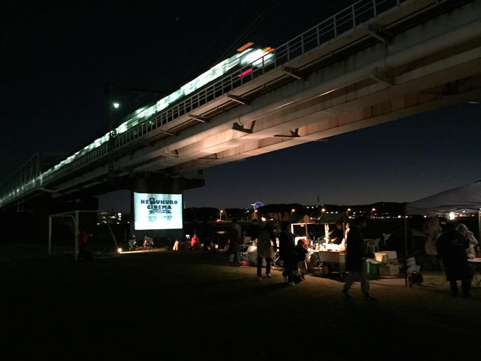 多摩川で行われた、ねぶくろシネマの模様。上映中も電車が走るが、その時の音も含めた臨場感が醍醐味。