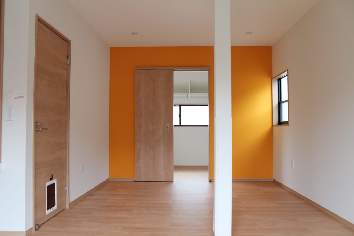 ビビットなオレンジの壁紙が部屋を明るい印象に