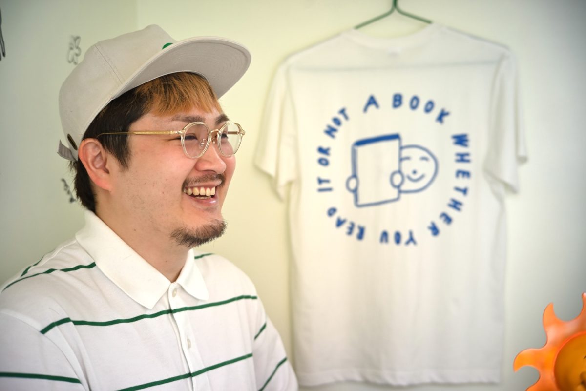 この日は2人お揃いの帽子とシャツで店番。壁にかかったオリジナルTシャツにあしらっているのは「読んでも読まなくても本は本」という佐古さんのメッセージ