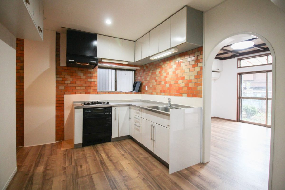 L字型のキッチン。壁のタイルもオシャレ。食器棚を置いても導線確保はばっちり。床下収納もあるとか